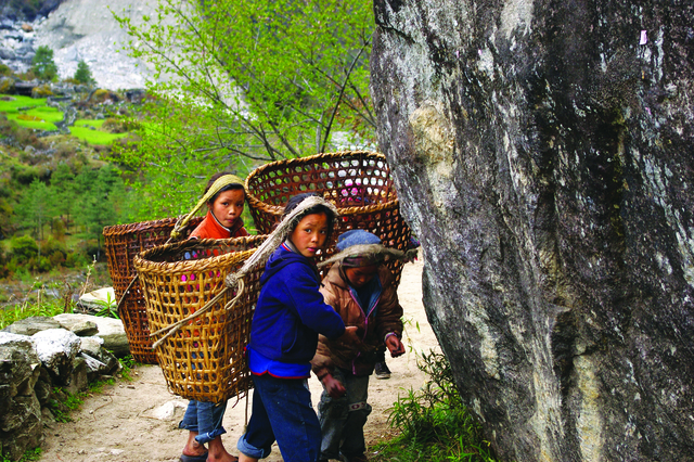 Sherpa children carrying baskets strapped to their heads