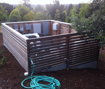 Exterior view of the slatted wood enclosure used to house the pool's elaborate and noisy pumps, electrical boxes, and plumbing before installation of Acoustifence and QuietFiber.