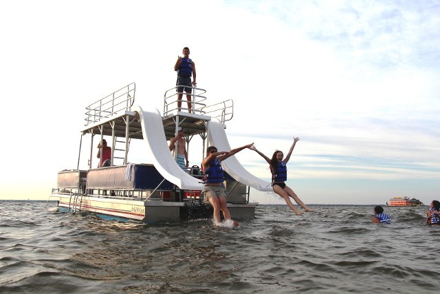 Kids watersliding off double-decker pontoon boat in Destin FL.