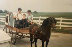 Steve Stoltzfus Jr, Owner of Sheds Unlimited, delivering dog boxes as a young boy. He built the cart that is being pulled by the family pony.