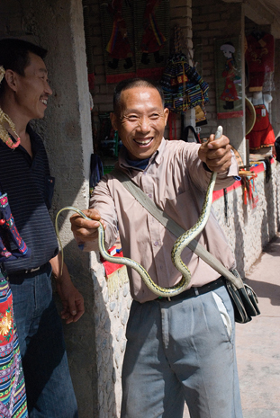 Yangtze River: The Lesser Three Gorges or Shennong Stream. Upper Shennong Stream.  A shopkeeper proudly displays a water-snake caught in the stream which will now be part of his evening meal.